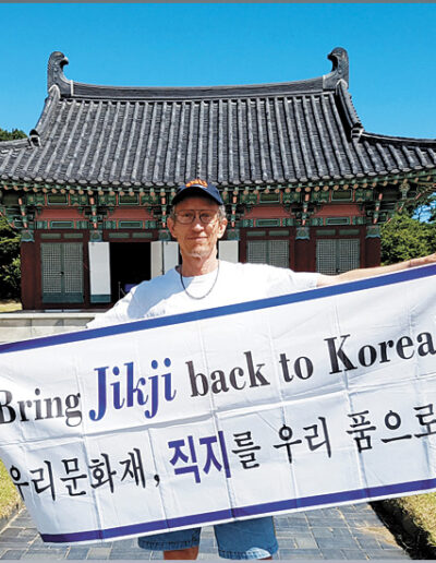 Richard Pennington, an American petitioning for the return of “Jikji” to Korea, holds up his campaign’s banner on the grounds where the Heungdeok Temple, the book’s printing site, once stood in Cheongju, North Chungcheong, on 27 August 2016